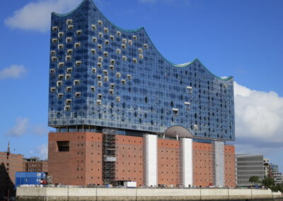 Das moderne Elbphilharmonie-Gebäude in Hamburg zeigt eine charakteristische Glaskuppel mit wellenförmiger Dachkontur auf einem massiven roten Backsteinunterbau.