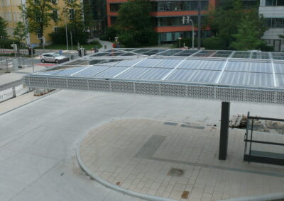 Eine moderne urbane Terrasse mit Solarpanelen über einem gepflasterten Platz, umgeben von zeitgenössischen Mehrfamilienhäusern.