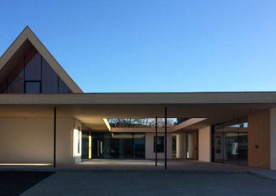 Ein modernes Gebäude mit flachem Dach, großzügiger Glasfassade und überdachtem Eingangsbereich prägt diese zeitgenössische Architektur.
