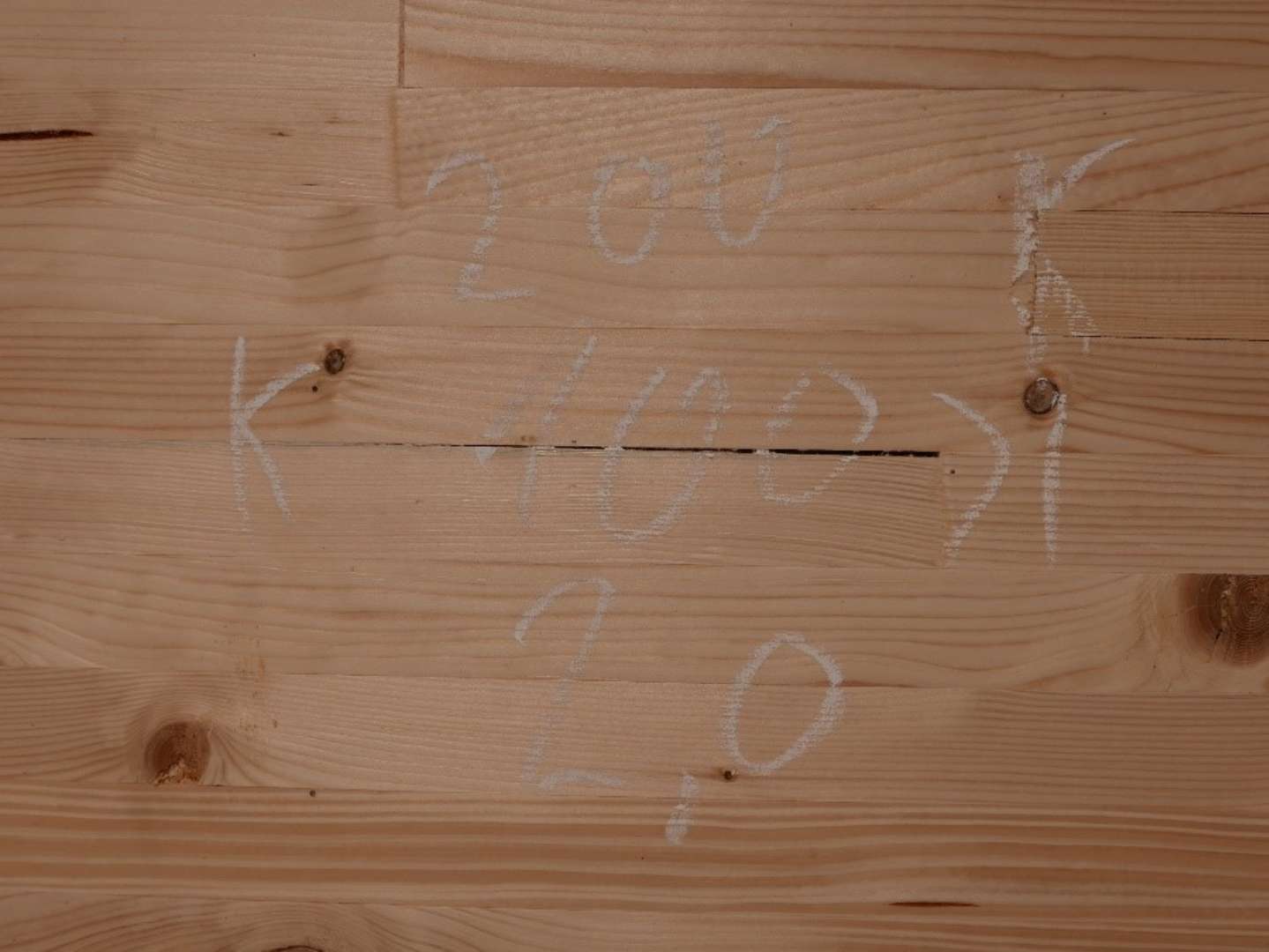 Auf Holzbrettern geschriebene Zahlen und Markierungen dokumentieren vermutlich Bauvermessungen oder Konstruktionsarbeiten.