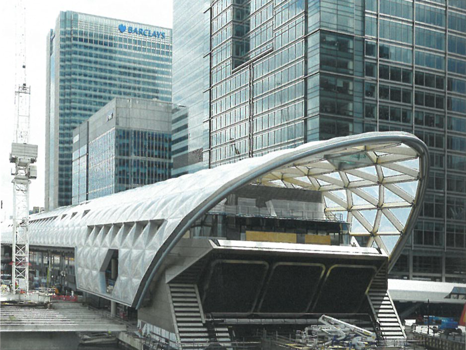 Ein futuristisches, silbernes Gebäude mit geschwungener Architektur steht vor modernen Hochhäusern in einer urbanen Skyline.